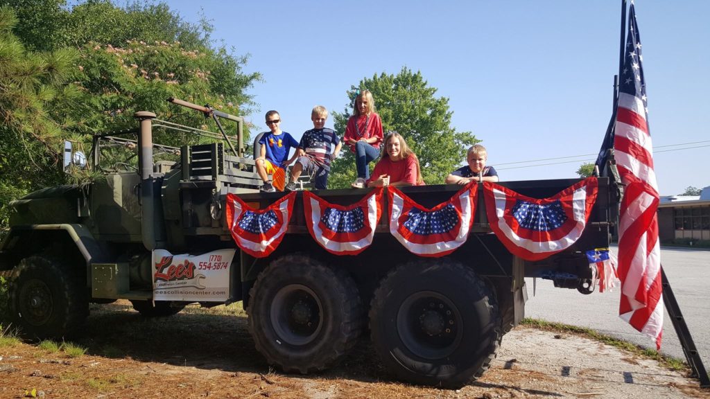 Children in a military truck decorated with American flags ready for the parade